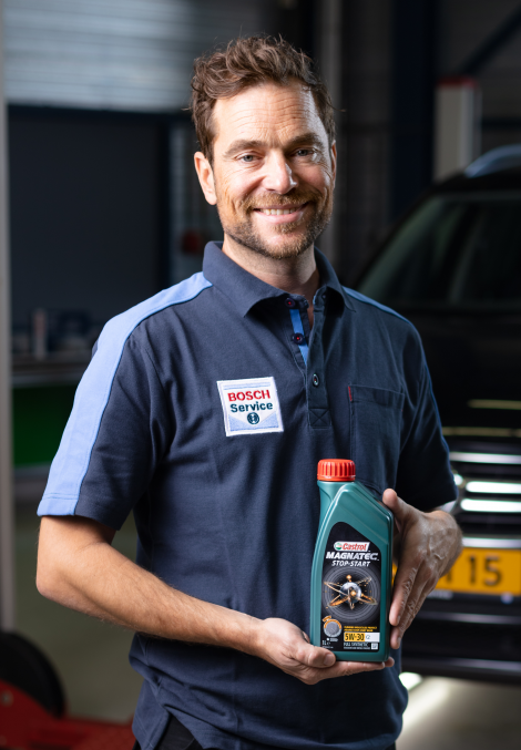 Le mécanicien Bosch Car Service détient une bouteille d'huile moteur de Castrol